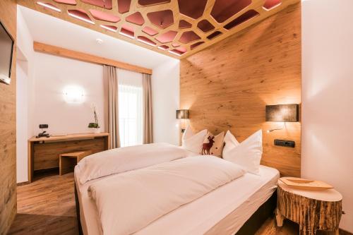 a bedroom with a large bed with a wooden ceiling at Hotel Laurin in Dobbiaco