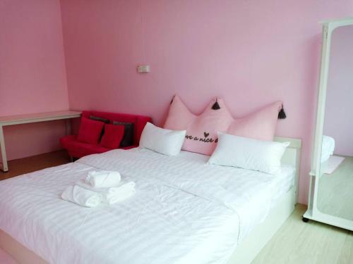 a pink bedroom with a white bed with a red chair at CJ Home-ex Micasa shoplot in Sibu