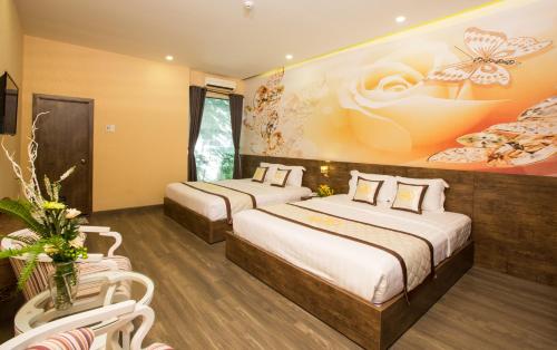 two beds in a room with a painting on the wall at Sang Như Ngọc Resort in Chau Doc