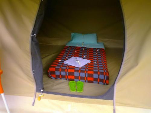 a tent with a bed and green shoes in it at Mwanzo Lodge in Naivasha