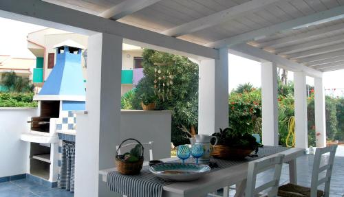un patio con una mesa y una pérgola blanca en Villa Salina fronte mare, en Santa Maria del Focallo