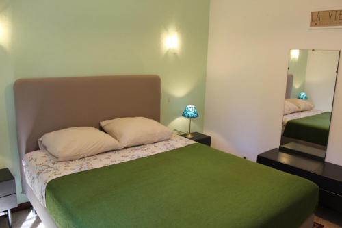 een slaapkamer met een groen bed en een spiegel bij Maison Charrasse in Flassan