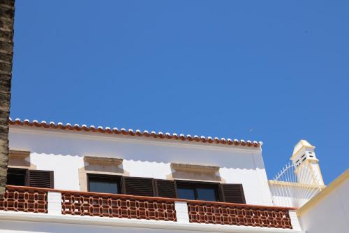 a white building with black shutters and a blue sky at Casa Malpique in Albufeira