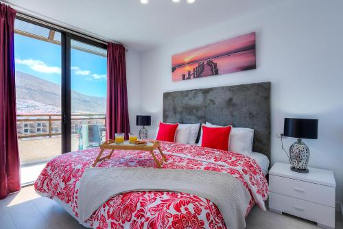 a bedroom with a large bed with red pillows at Modern Apartment Los Cristianos Center in Los Cristianos