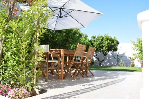 een houten tafel en stoelen met een parasol bij Dimora Santa Caterina in Conversano