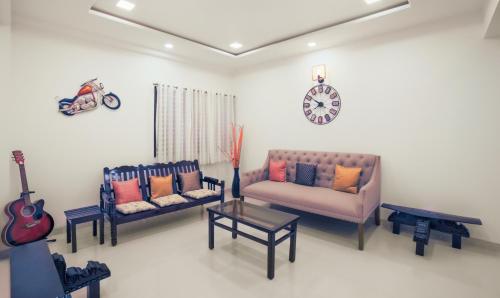 a living room with two couches and a guitar at Treebo Trend Chalets, Nagpur Airport in Nagpur