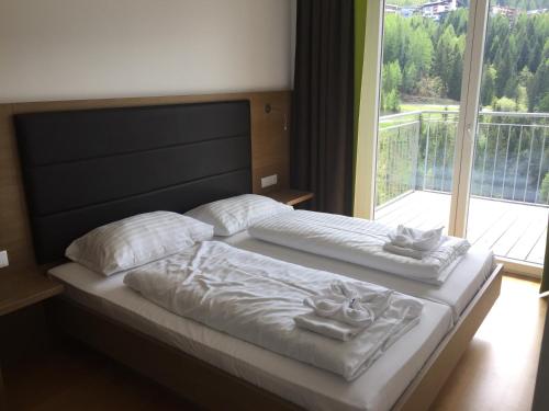 ゾンネンアルペ・ナスフェルトにあるNassfeld Mountain Apartmentsのベッド1台(白い枕2つ付)、窓が備わります。