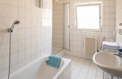 a white bathroom with a tub and a sink at Gästezimmer Strauß in Kottenheim