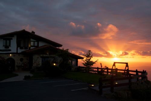 a sunset over a house with the sun setting at Agroturismo Maddiola in Donostia-San Sebastián