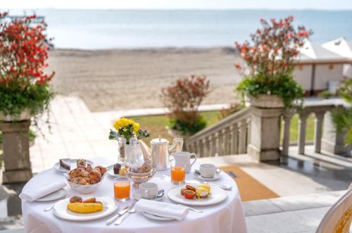 a table with plates of food on a balcony with the beach at Hotel Excelsior Venice in Venice-Lido