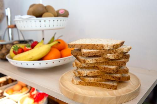 a stack of bread on a cutting board with a bowl of fruit at Bristol Logis Cit'Hotel Périgueux Centre in Périgueux