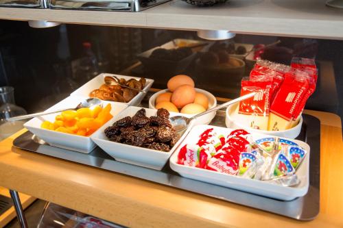 a shelf with several bowls of food on a table at Bristol Logis Cit'Hotel Périgueux Centre in Périgueux