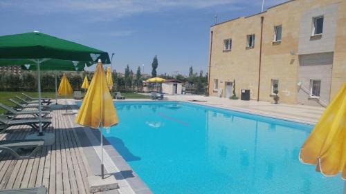 a swimming pool with umbrellas and chairs and a building at Casablanca Garden Hotel in Nevşehir
