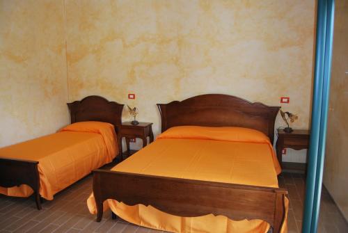 レンデにあるAgriturismo La Turritellaのオレンジのシーツが備わる客室内のベッド2台