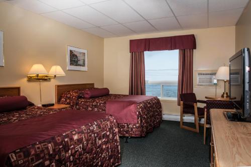 Shallow Bay Motel & Cabins Conference Centre في Cow Head: غرفه فندقيه سريرين وتلفزيون