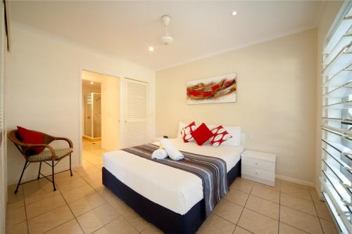 a bedroom with a bed and a chair at Mango House Resort in Airlie Beach