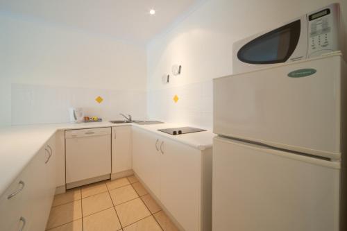 a white kitchen with a sink and a refrigerator at Mango House Resort in Airlie Beach