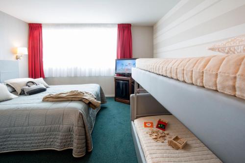 a hotel room with two beds and a television at Bristol Logis Cit'Hotel Périgueux Centre in Périgueux