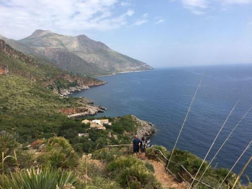 a man standing on a hill looking at the ocean at Palms Villa in Scopello