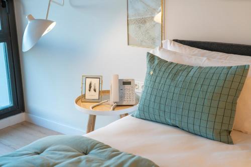a bed with a green and white pillow next to a table at IXUA Hotela in Éibar