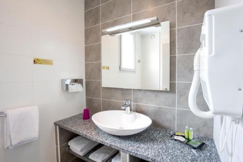 a bathroom with a sink, toilet and mirror at Bristol Logis Cit'Hotel Périgueux Centre in Périgueux