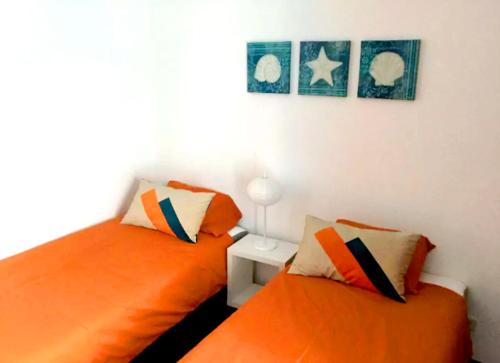 フォス・ド・アレーリョにあるFoz do Arelho Beach Apartment "Blue"のベッドルーム1室(オレンジ色のベッド2台、テーブル付)