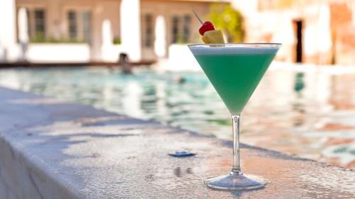 a drink sitting on a ledge next to a swimming pool at Alentejo Marmòris Hotel & Spa, a Small Luxury Hotel of the World in Vila Viçosa