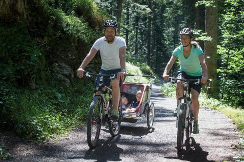 two people riding bikes with a child in a cart at Soldanella by Hotel Adula in Flims