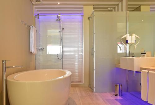 a bathroom with a tub and a glass shower at Pestana Alvor South Beach Premium Suite Hotel in Alvor