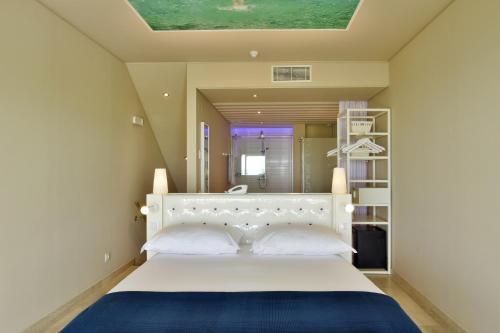 1 dormitorio con cama blanca y manta azul en Pestana Alvor South Beach Premium Suite Hotel en Alvor