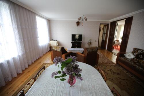 a living room with a table with a vase of flowers on it at Ismayilli Guest House in İsmayıllı