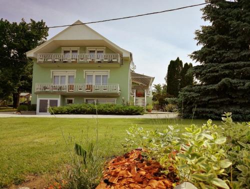 a green house with a balcony on a yard at Elisoria Apartments in Cserszegtomaj