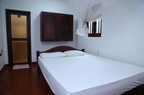 a bedroom with a white bed and a door at Holiday Home Bentota in Bentota