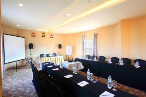 a conference room with tables and chairs and a screen at Gino Feruci Braga by KAGUM Hotels in Bandung