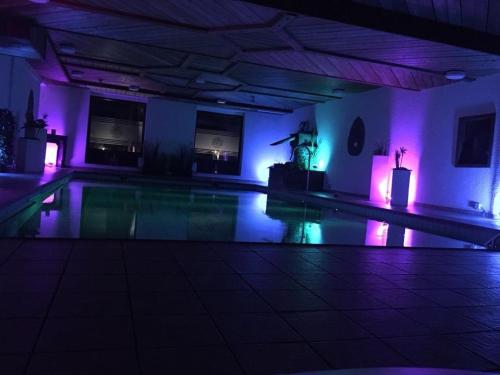 a swimming pool with purple lights in a room at hotel zentlinde in Mossautal