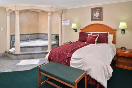 a bedroom with a large bed and a bath tub at Americas Best Value Inn Lubbock East in Lubbock