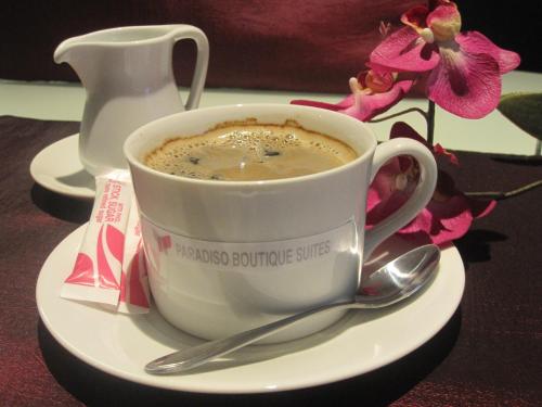 a cup of coffee on a plate with a spoon at Paradiso Boutique Suites in Bangkok