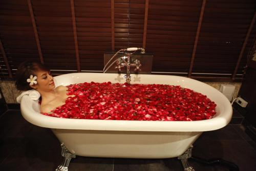 una mujer sentada en una bañera llena de pimientos rojos en Suvarnabhumi Suite Hotel en Lat Krabang