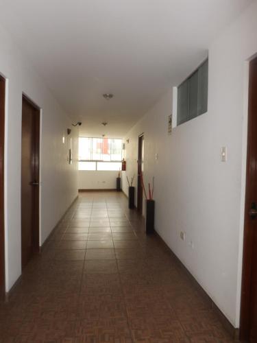 un pasillo vacío con paredes blancas y suelo de baldosa en Venecia Hotel Carrion, en Trujillo