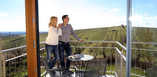 a man and a woman standing on a balcony at Wohlfühlhotel Alte Rebschule in Rhodt unter Rietburg