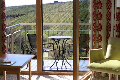 a room with a balcony with a table and chairs at Wohlfühlhotel Alte Rebschule in Rhodt unter Rietburg