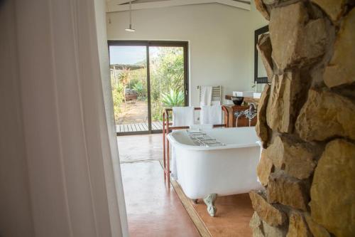 bañera en una habitación con pared de piedra en Hopewell Private Game Reserve, en Buyskloof