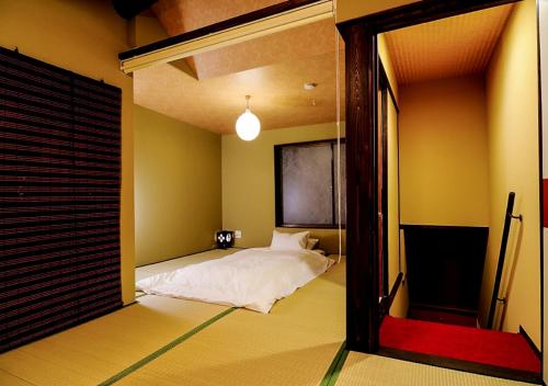 een slaapkamer met een bed in een kamer met een spiegel bij Kyoto Miyabi Inn in Kyoto