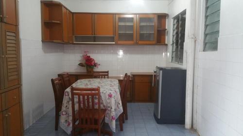 una pequeña cocina con mesa, sillas y nevera. en GuestHouse Taman Megah, Lot 19, en Sandakan