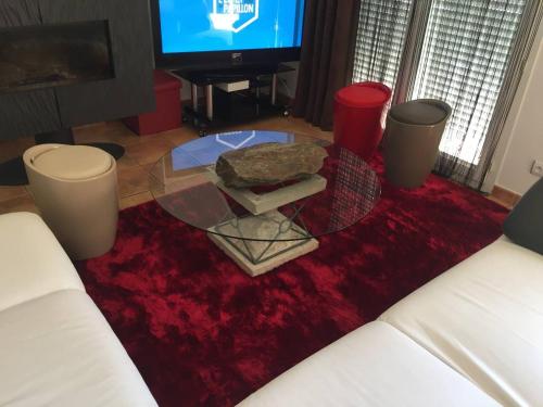 un soggiorno con un tavolo in vetro su un tappeto rosso di Chambre dans une villa a Beaupuy