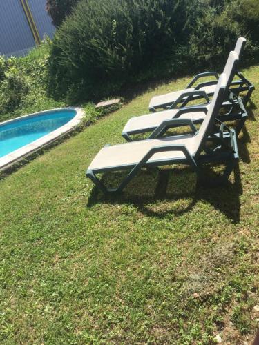 uma fila de espreguiçadeiras sentadas ao lado de uma piscina em Chambre dans une villa em Beaupuy