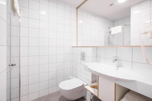 a white bathroom with a toilet and a sink at #draugunamai in Druskininkai