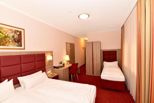 a hotel room with two beds and a desk at Hotel Römerhof in Baden-Baden