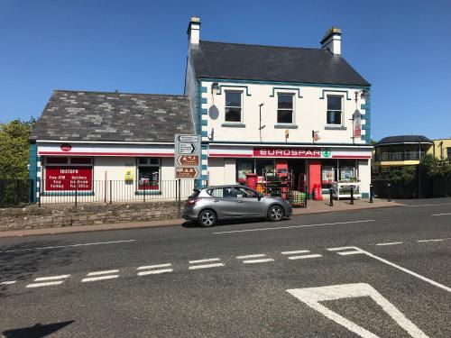 a car parked in front of a building on a street at Ballymacdoe Cottage Cushendall in Cushendall