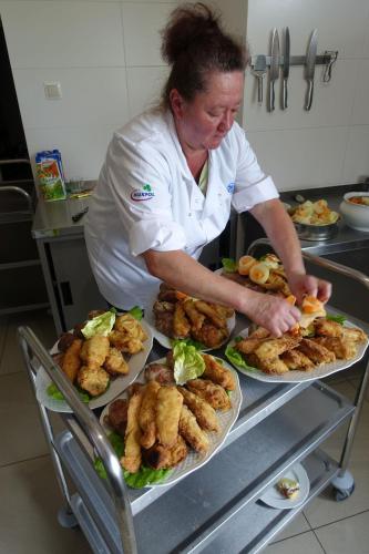 a woman preparing food in a kitchen with plates of food at Willa Zaolzie in Istebna